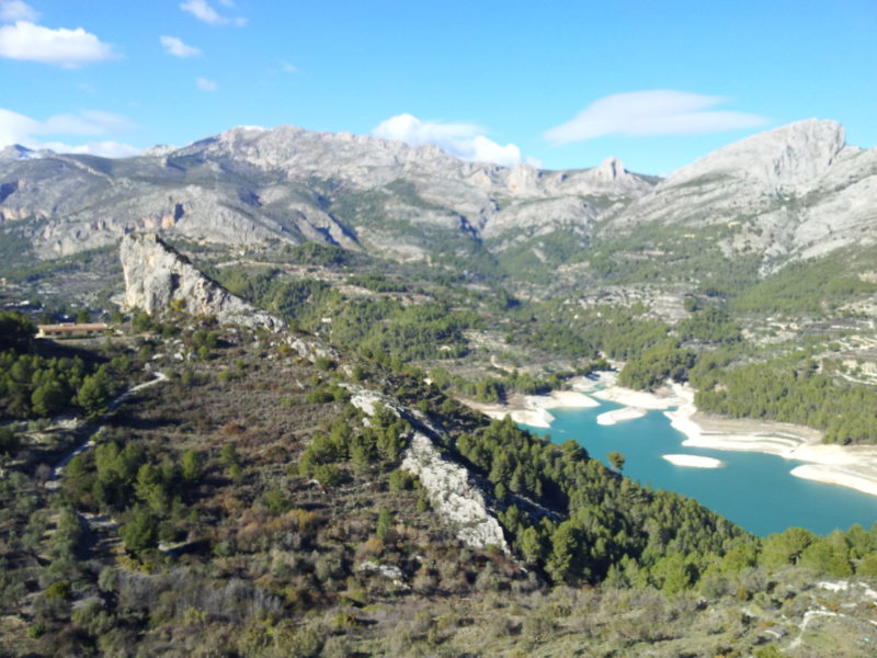 Blue lake, mountains surrounding, rocks and pine trees.