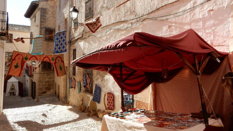 White walls, market stall, flags and tapestry.